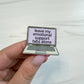 A hand holding an enamel pin shaped like a laptop computer screen with the text 'leave my emotional support tabs alone' on a light marble background.